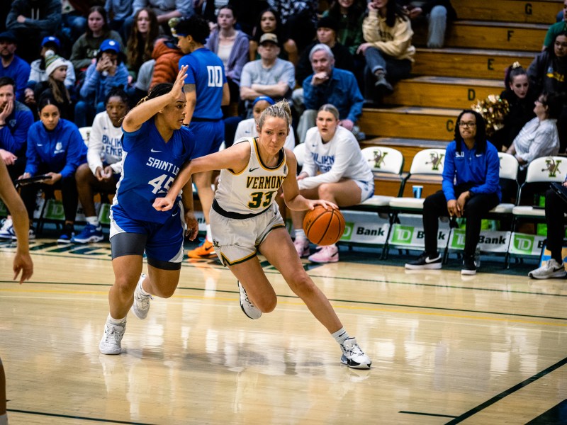 A basketball player dribbles the ball past a defender.