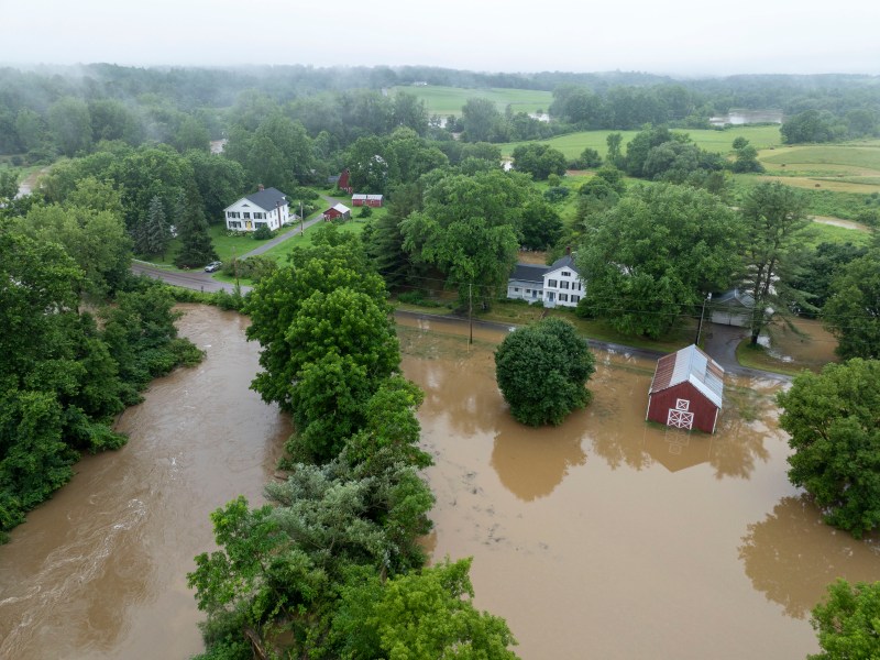 Aerial view of a flooded rural area showing submerged roads, properties, and surrounding fields with significant floodwater levels.