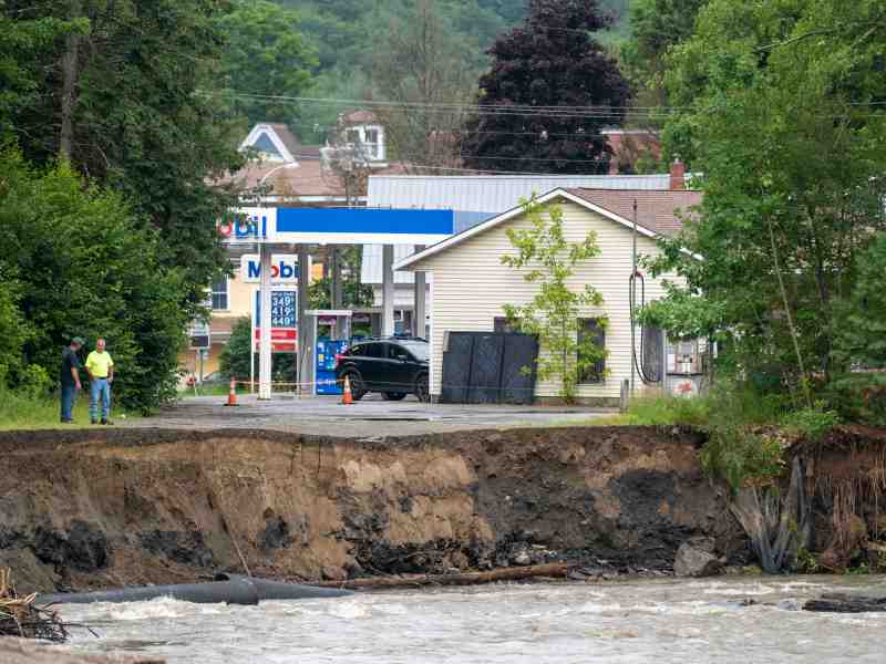 Two men look down at the eroded banks of a river