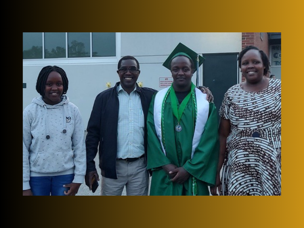 A group photo with four people: a young woman in a hoodie, two adults, and a young man in a green graduation outfit.