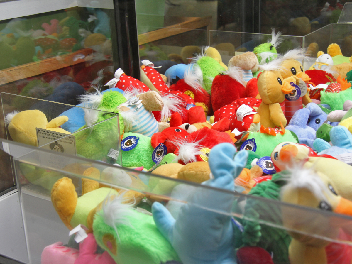 A claw machine filled with various colorful stuffed animals and plush toys.