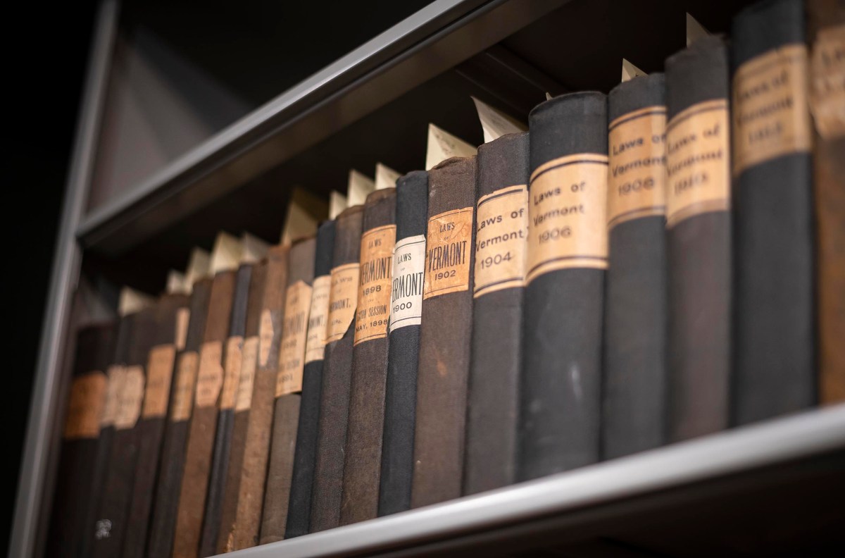 A row of black and brown hardcover books with dated labels on a metal shelf.