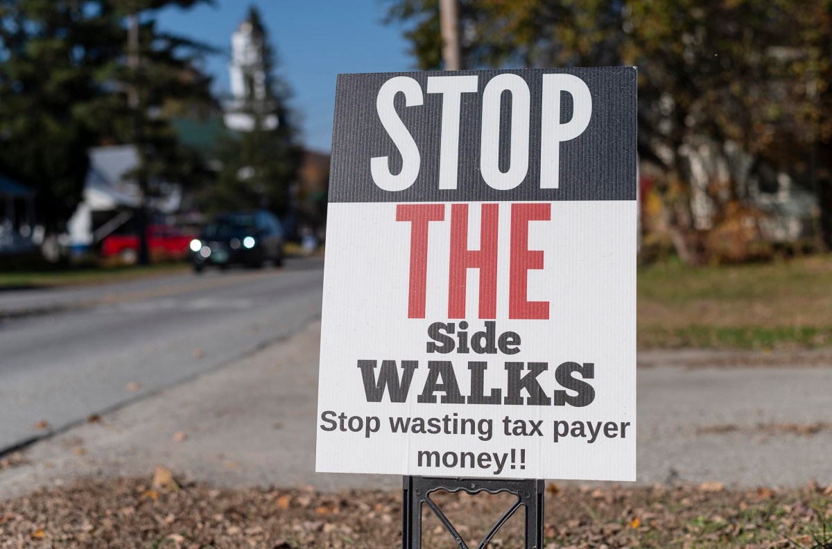 A sign by the roadside reads, "Stop the Sidewalks. Stop wasting taxpayer money!.
