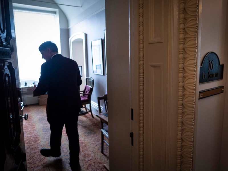 Person entering a room marked "16 Lt. Governor" with a patterned carpet and a large window in the background.
