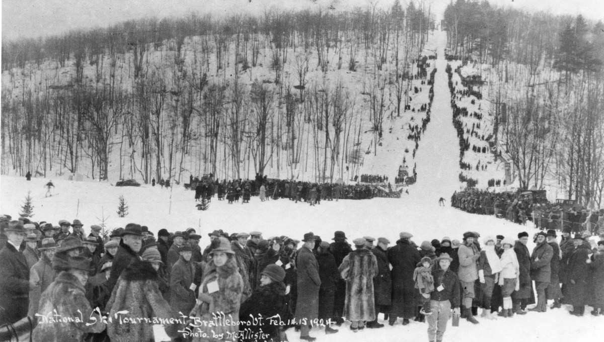Large crowd watches a skier on a long slope at the National Ski Tournament in Salisbury, Vermont, February 11, 1924. Snow-covered landscape with trees in the background.