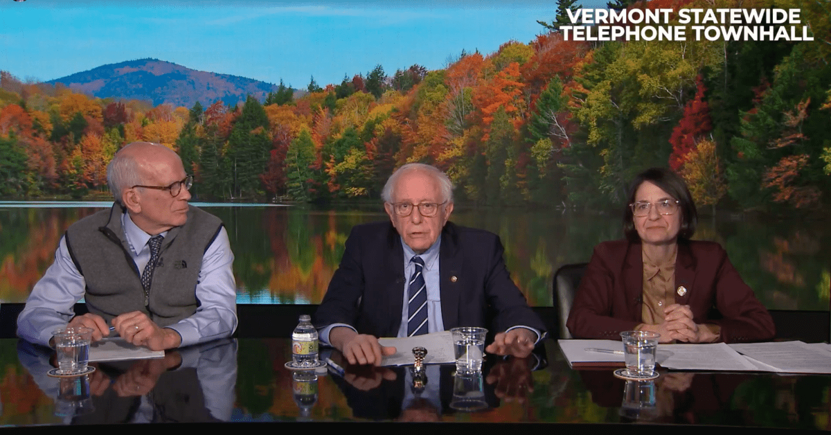 Three people sitting at a table during a Vermont Statewide Telephone Townhall, with a scenic fall landscape backdrop.