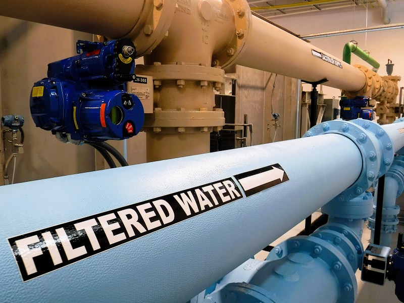 Industrial pipes with labels, including a large blue pipe marked "Filtered Water" with an arrow indicating flow direction.