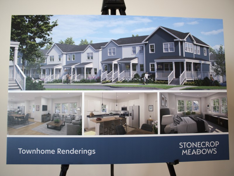 A poster displays renderings of townhomes with exterior and interior views, labeled "Townhome Renderings." The poster is titled "Stonecrop Meadows.
