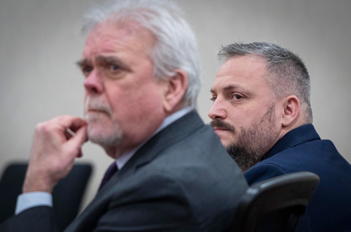 Two men in suits seated in a meeting room; one in focus attentively listening, the other slightly blurred in the foreground.