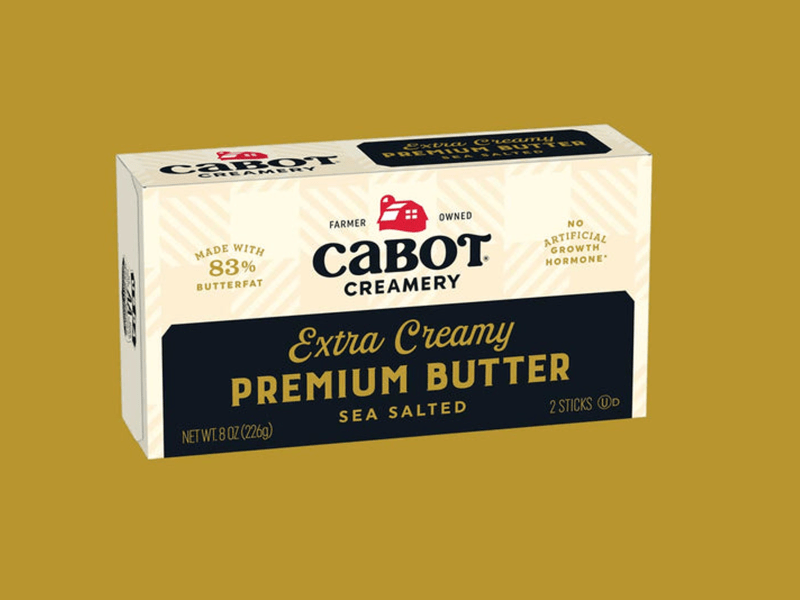 Box of Cabot Creamery Extra Creamy Sea Salted Premium Butter with 83% butterfat on a mustard yellow background.