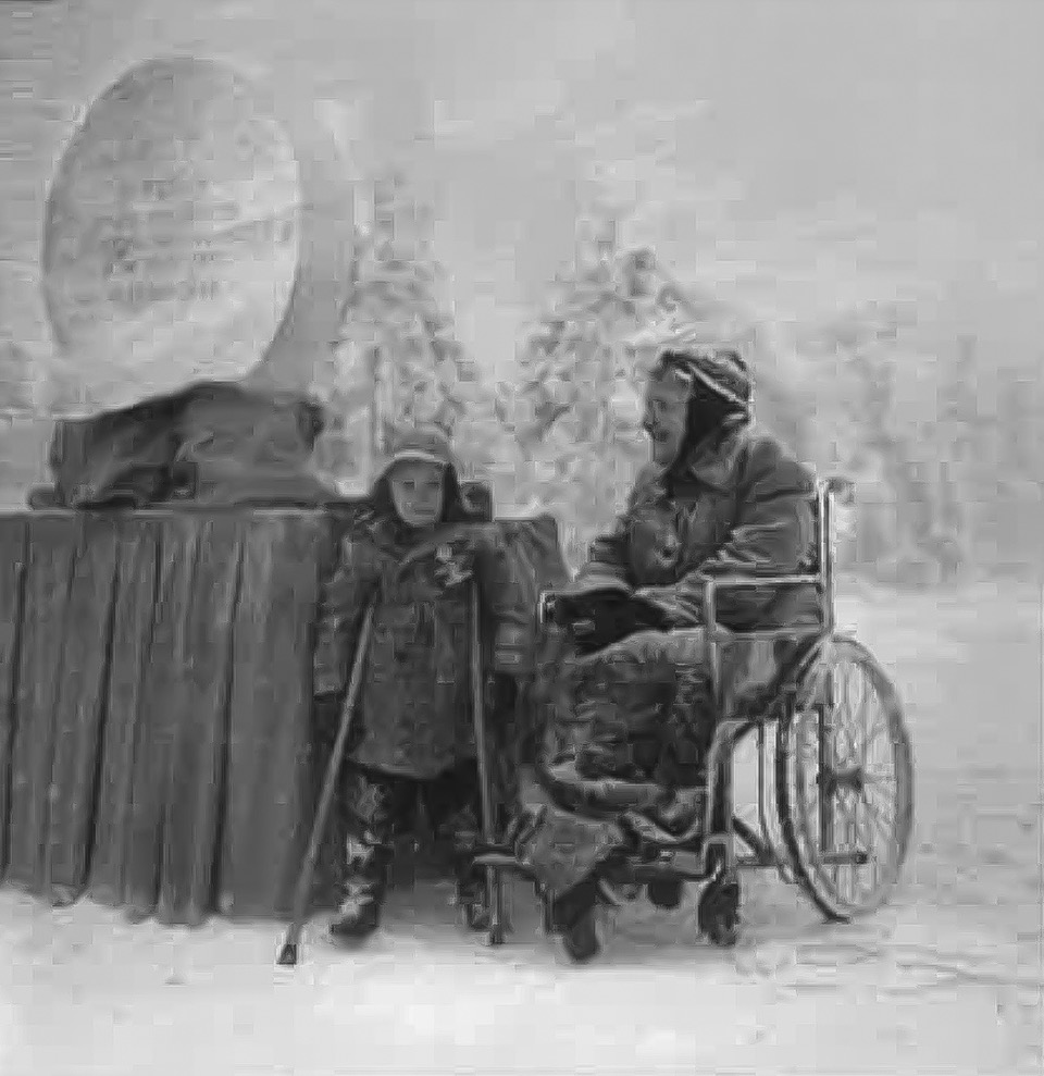 Two people bundled in winter clothing, one standing with crutches and the other sitting in a wheelchair, are outdoors in heavy snow beside a covered table with a large round object.