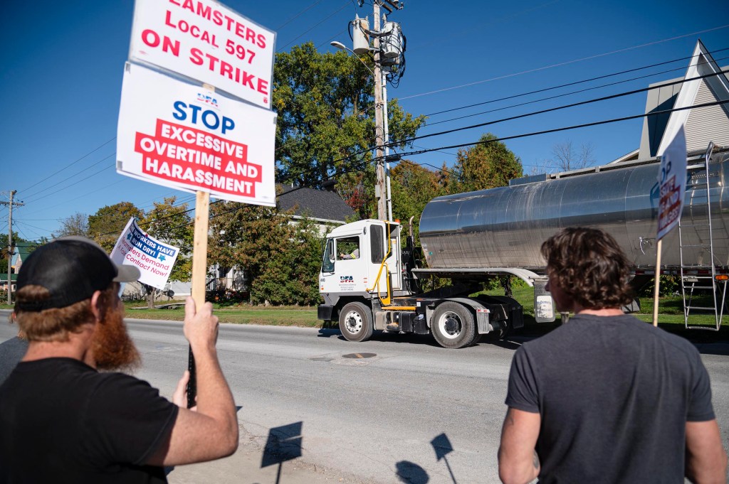 Two people hold picket signs reading 