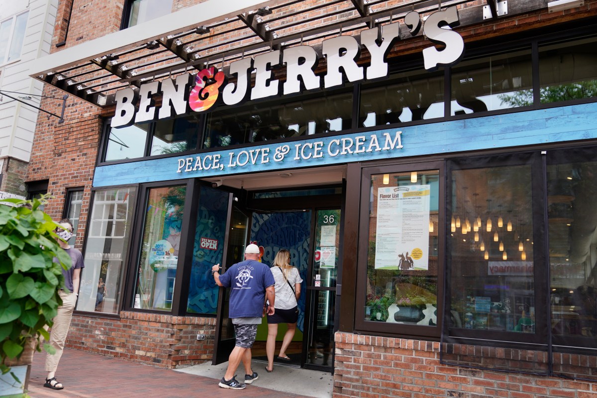 People enter a Ben & Jerry's ice cream shop with a sign reading "PEACE, LOVE & ICE CREAM" above the entrance.