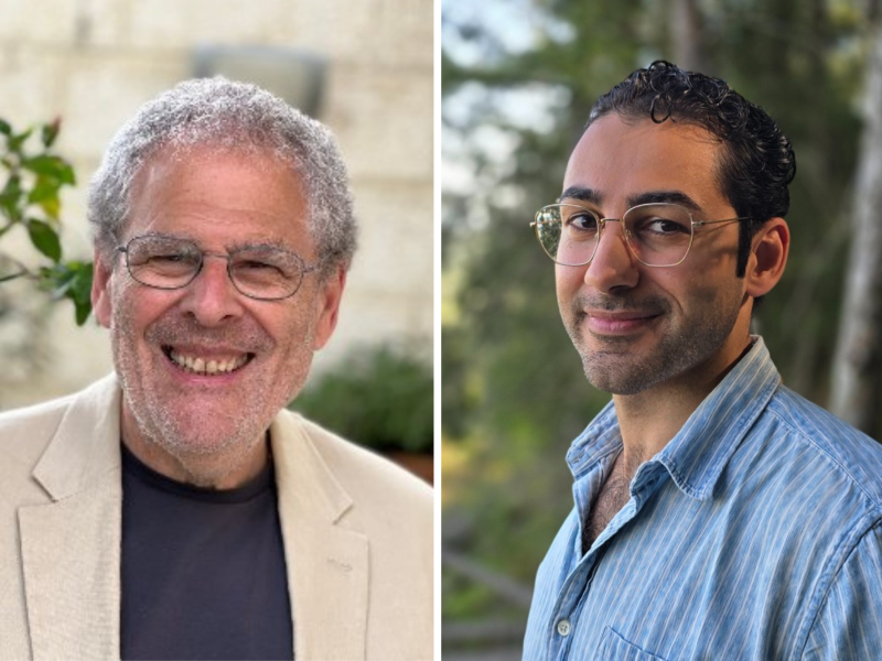 Two men are pictured side by side; the left man has gray hair and glasses, wearing a beige jacket, and the right man has dark hair and glasses, wearing a blue striped shirt.