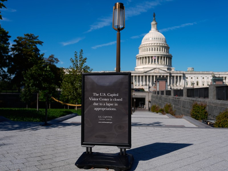 A sign in front of the U.S. Capitol Visitor Center reads “closed due to a lapse in appropriations;” the Capitol dome is visible in the background under a clear blue sky.
