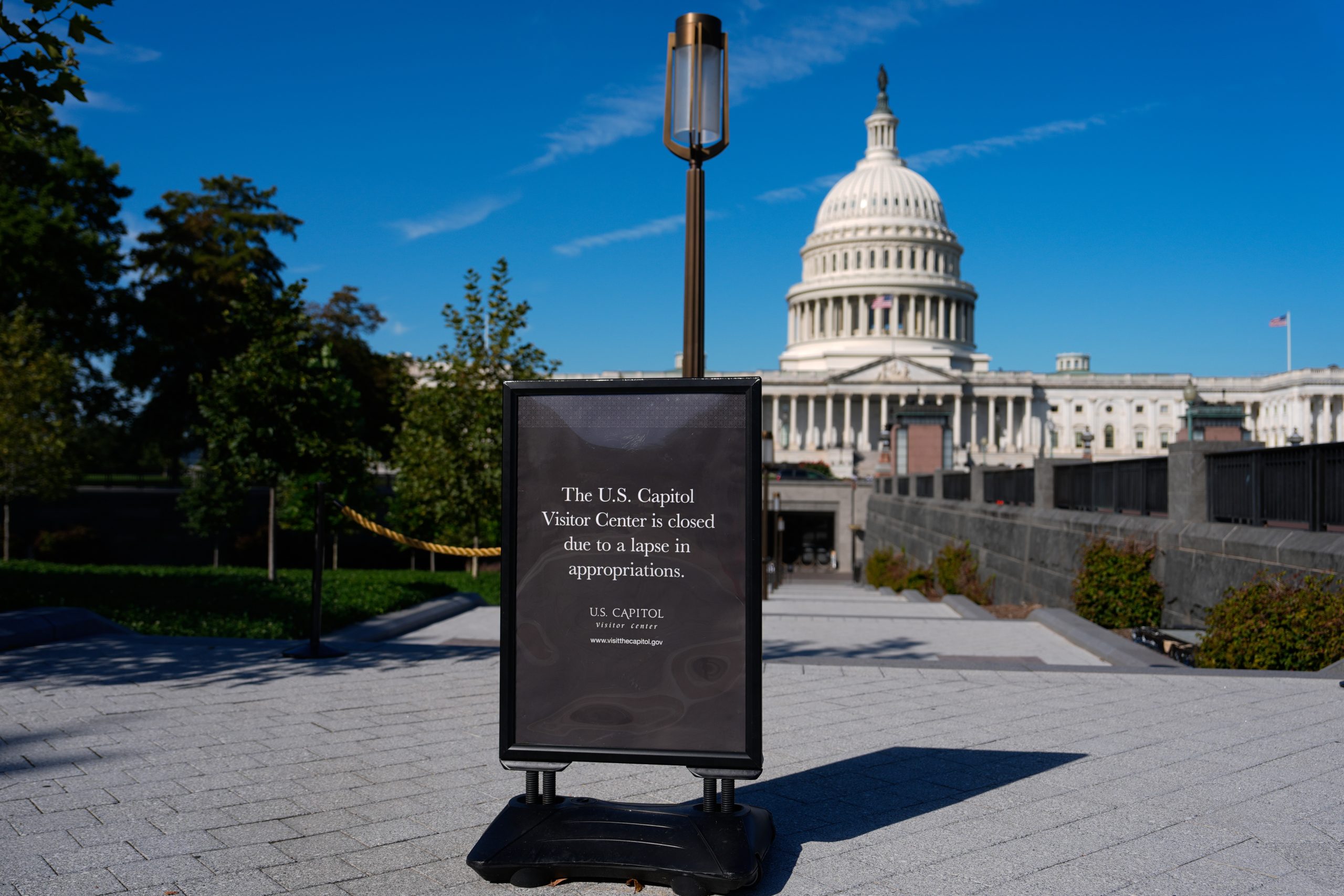 A sign in front of the U.S. Capitol Visitor Center reads “closed due to a lapse in appropriations;” the Capitol dome is visible in the background under a clear blue sky.