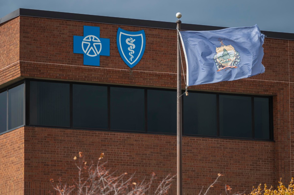 A brick building displays Blue Cross Blue Shield logos, with a state flag on a pole waving in front of it.