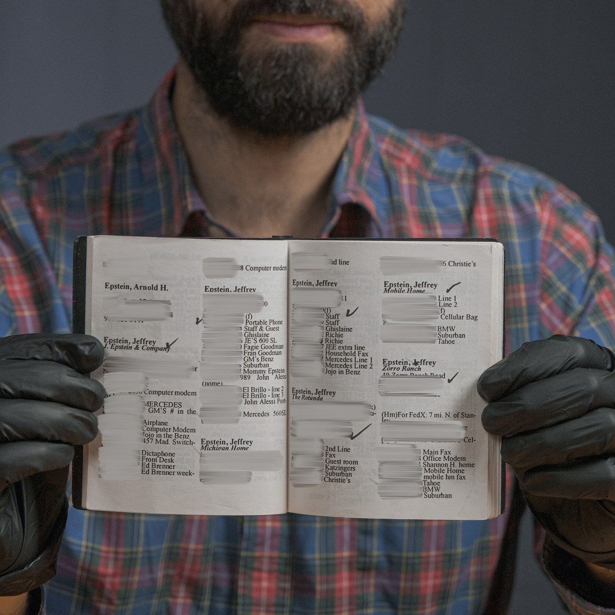 A person wearing black gloves and a plaid shirt holds open a small address book with several entries blacked out and the name “Epstein, Jeffrey” visible multiple times.