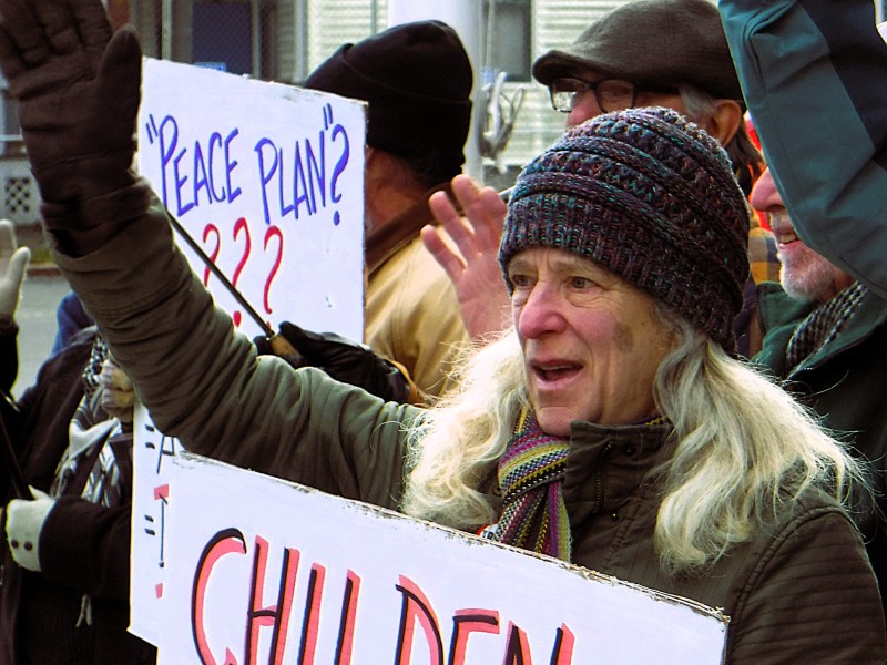 A group of people protest outdoors in winter clothing, holding signs that read "Peace Plan???" and "Children.