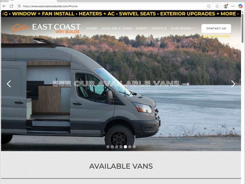 A silver camper van is parked near a frozen lake with tree-covered hills in the background. Text on the image advertises available vans from East Coast Van Builds.