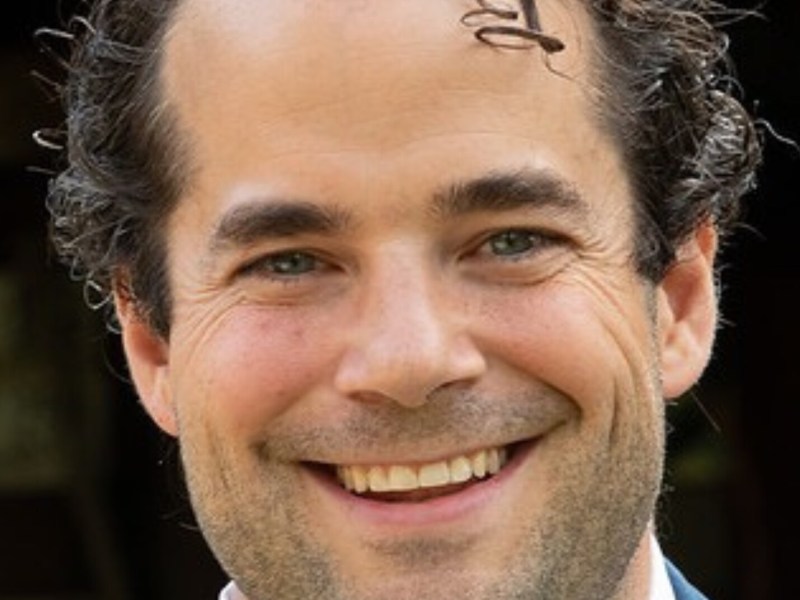 A headshot of a man smiling.