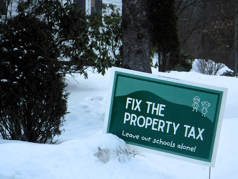 A sign in the snow with simple drawings of two children on a green background.