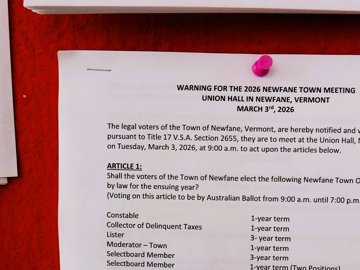 A notice about the 2026 Newfane town meeting in Vermont, posted on a bulletin board, details the election of town officers and meeting logistics.