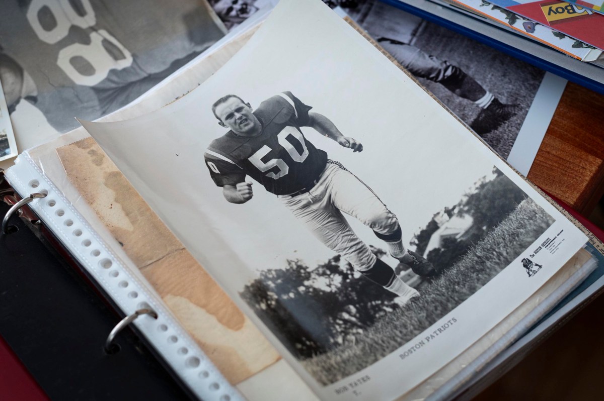 Black and white photo of a football player in uniform number 50 running on grass, placed in a binder with other documents and photos.