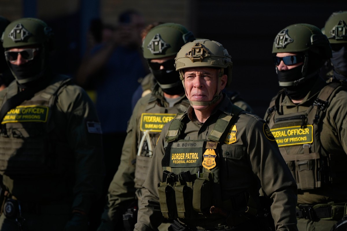 A group of uniformed federal officers, including a Border Patrol agent, stand together outdoors, wearing tactical gear and helmets.