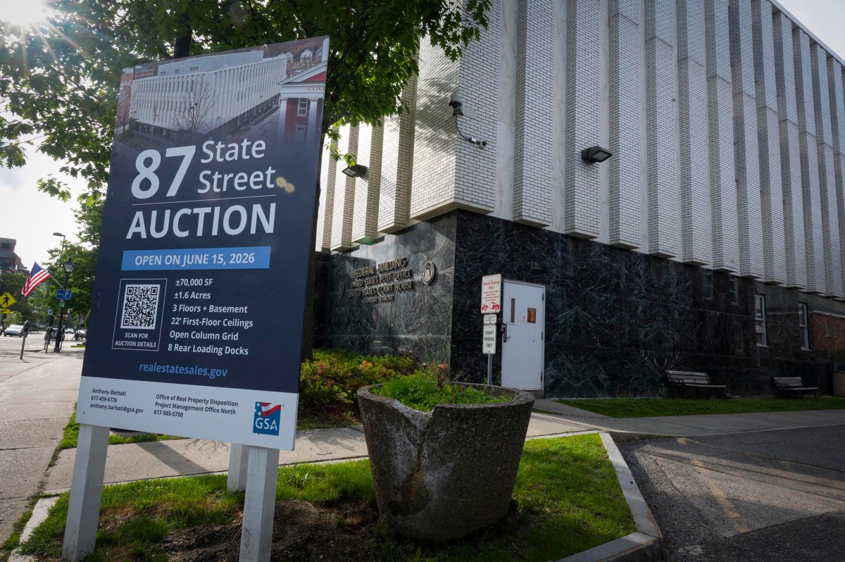 A large sign outside a building announces an auction for 87 State Street, detailing auction date, building features, and a government website for more information.