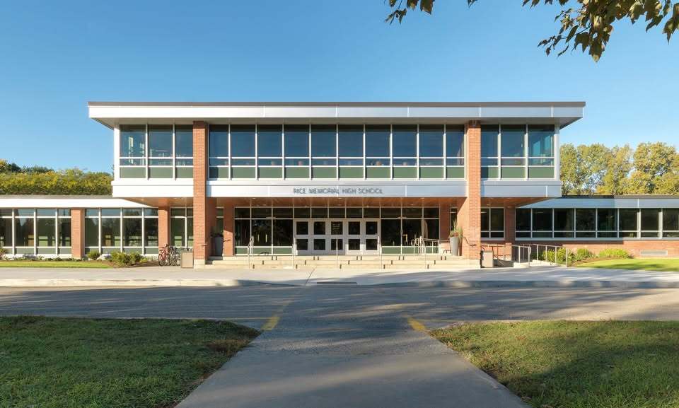 Front view of a modern two-story brick and glass school building with the sign “High School” above the entrance.