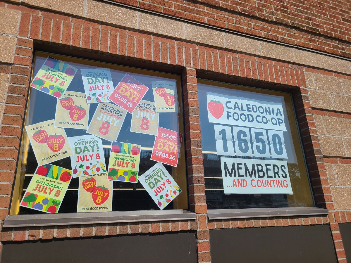 Storefront windows feature multiple “Opening Day July 8” signs and a large “Caledonia Food Co-op 1650 members and counting” sign.