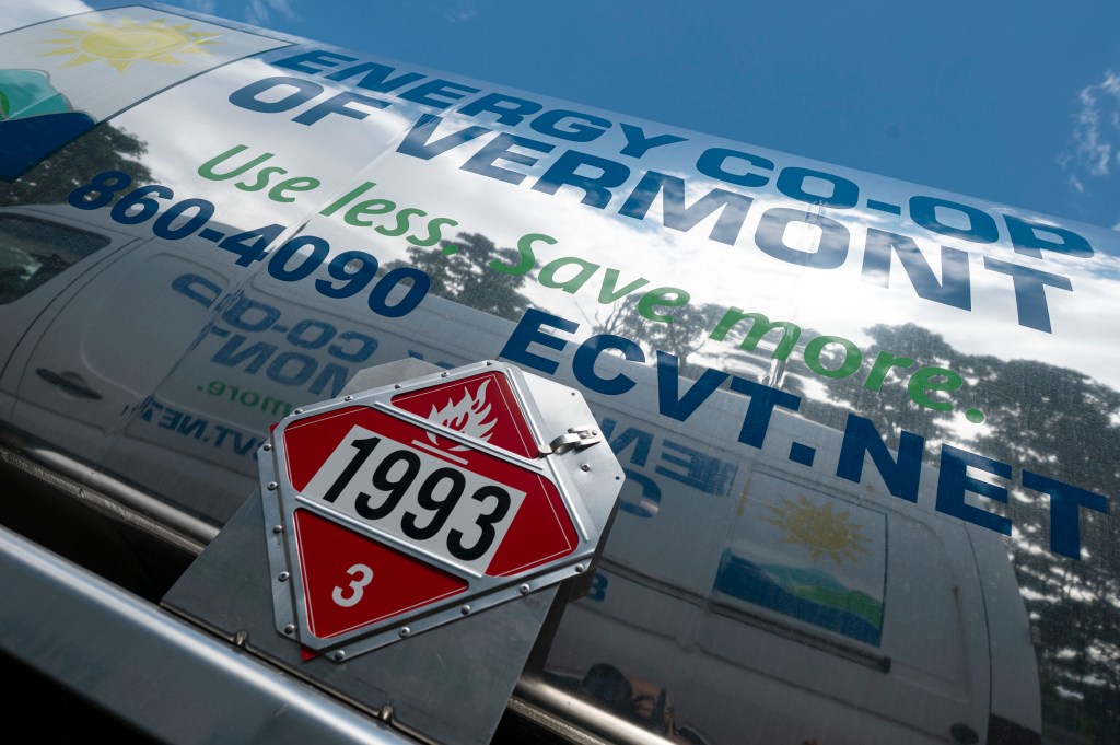 A close-up of an Energy Co-op of Vermont fuel truck displays contact information and a red hazardous materials sign labeled 1993.
