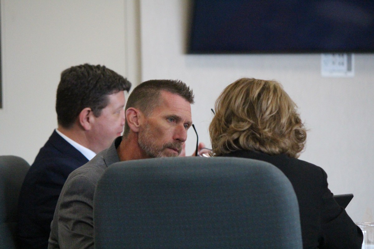 Three people in business attire are seated at a table, engaged in conversation during a meeting.