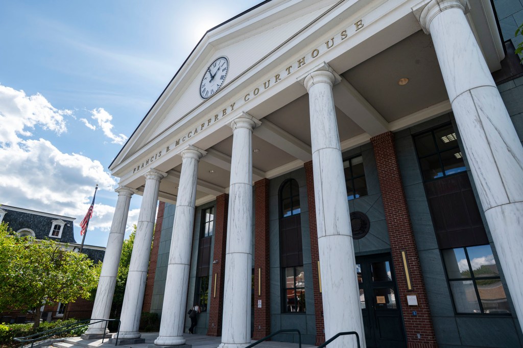 Front view of the McCaffrey Courthouse with white columns, a clock, and partly cloudy sky in the background.