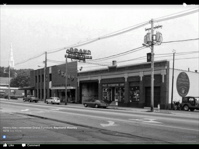 Black and white photo of Grand Furniture and Foley Distributing Corp. buildings on a city street in 1979.